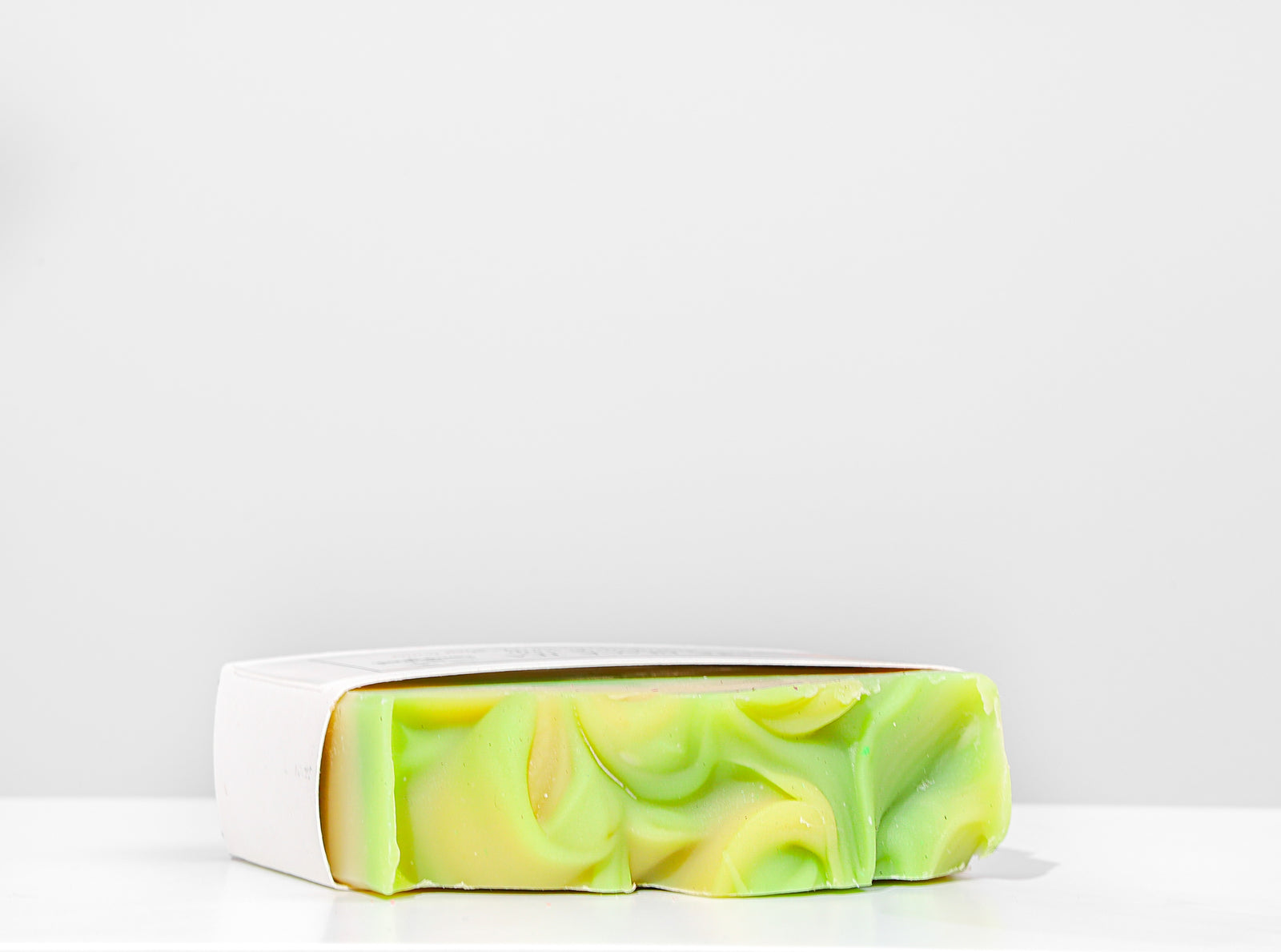 Handmade soap bar with green and yellow swirls on a white background